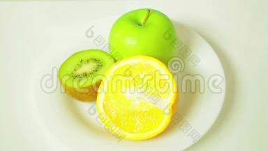 白色盘子里的橙皮猕猴桃和绿皮苹果的两半旋转成一个圆圈